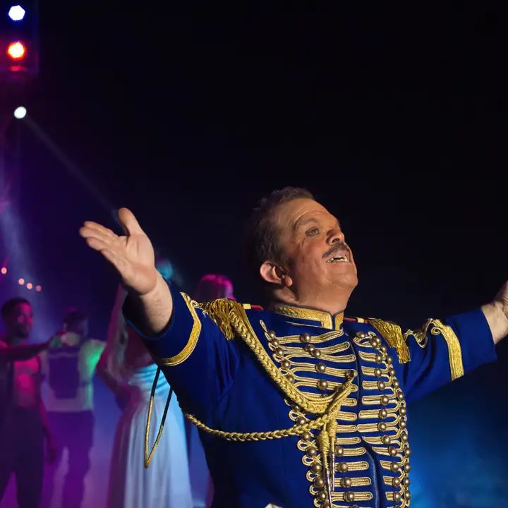 Spreekstalmeester Milko in blauw-gouden uniform verwelkomt het publiek in de piste